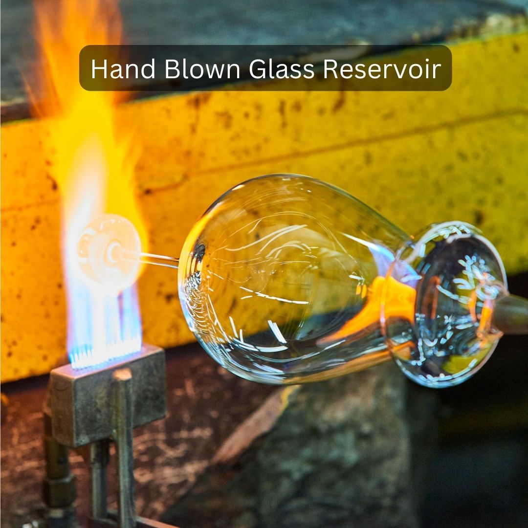Hand blown glass reservoir being worked on with a torch in a workshop setting.