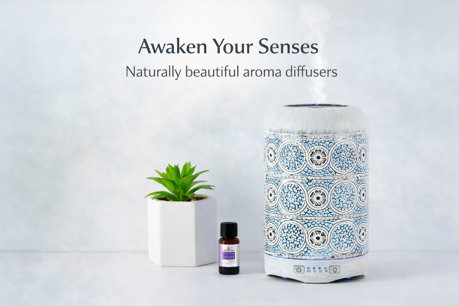 Aroma diffuser with decorative patterns, a small plant, and a bottle of essential oil on a light background.